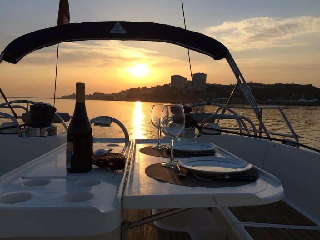 Mesa em cima do barco Douro Sailing com dois pratos do lado direito com duas taças ao lado e do lado esquerdo uma garrafa de vinho e ao fundo o rio Douro.
