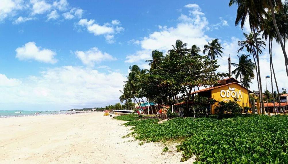Vista da Odoiá, um dos hotéis em Maragogi, sendo o local localizado pé na areia, num lugar com bastante vegetação e árvores. A areia da praia é clara e o mar azulado