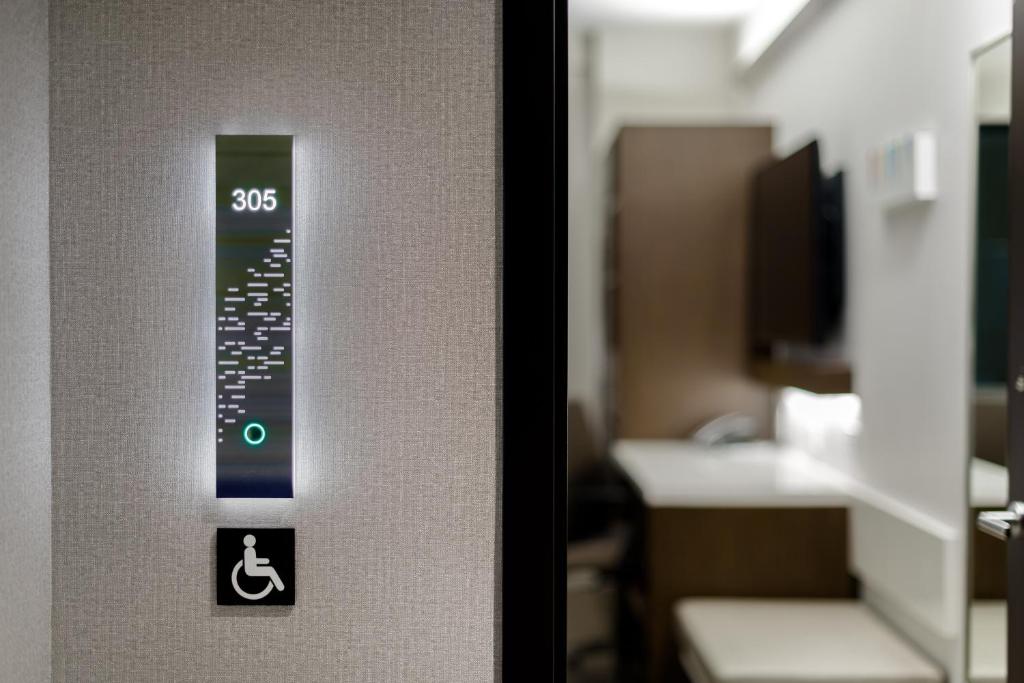A placa iluminada do quarto número 305 do Luma hotel, destacando-se contra uma parede de textura suave. A placa também indica que o quarto é acessível para pessoas com deficiência. Este é um dos hotéis em Nova York.