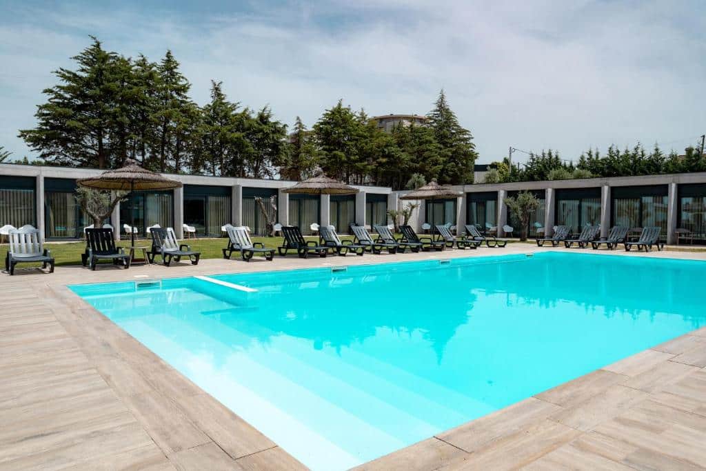 Piscina ao ar livre do Borralha Hotel, Restaurante & Spa durante o dia a frente da imagem e do lado esquerdo do piscina cadeiras.