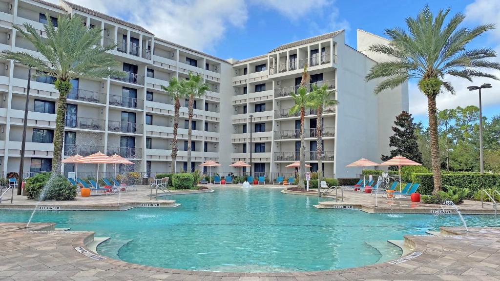 Piscina ao ar livre do Holiday Inn Orlando – Disney Springs com algumas palmeiras ao redor, além de espreguiçadeiras coloridas no deck
