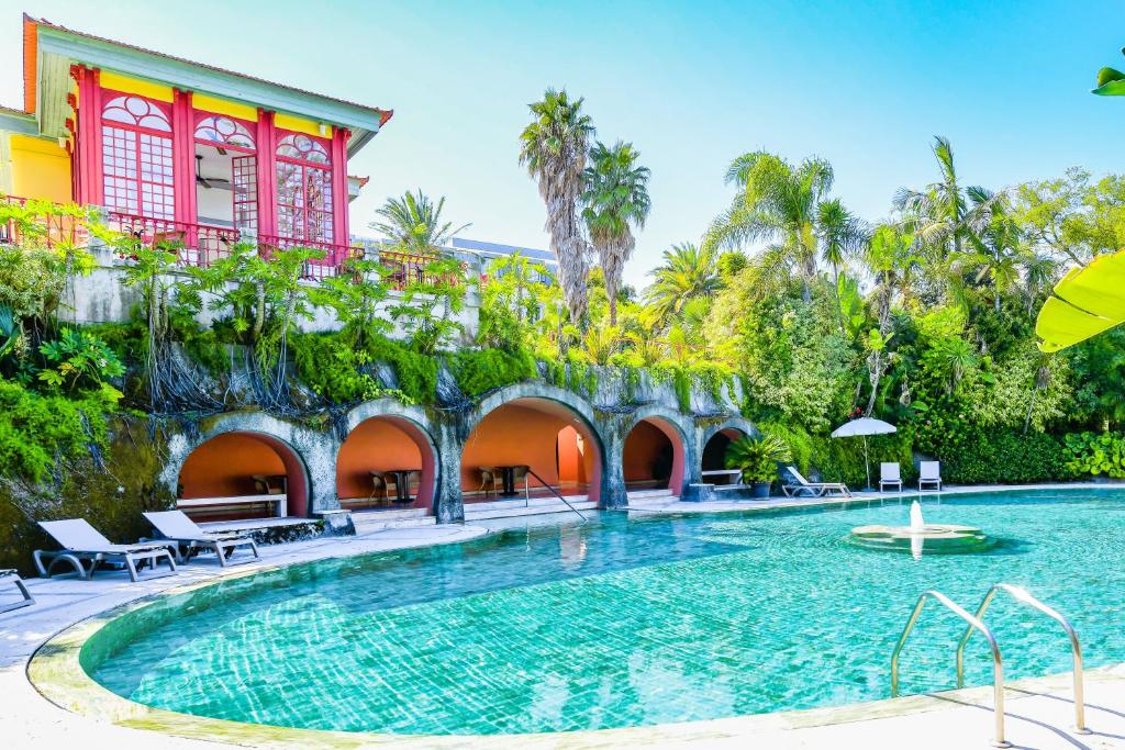 Piscina ao ar livre do Pestana Palace Lisboa Hotel & National Monument – The Leading Hotels of the World durante o dia com piscina a frente e ao fundo a estadia.