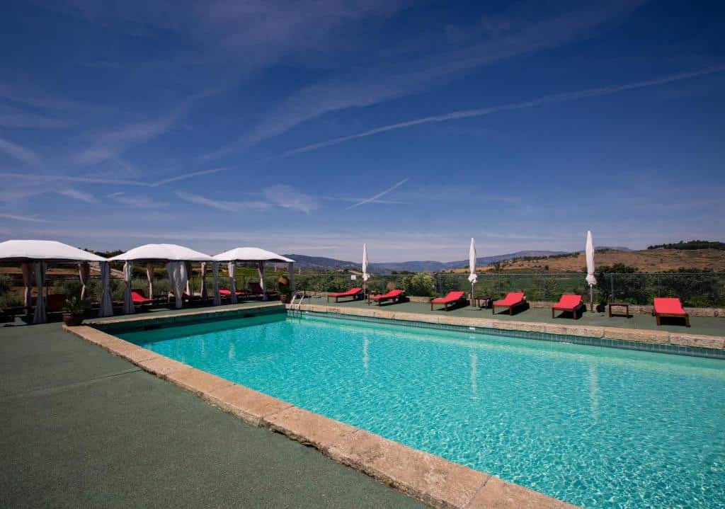 Área da piscina do Quinta da Barroca, durante o dia com piscina do lado direito da imagem, com cadeiras do lado direito da piscina.