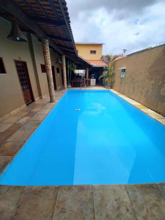 Parte da Pousada Pouso Da Praia que mostra a piscina azul e do lado esquerdo portas e pilastras da pousada e ao fundo outra parte da pousada, ilustrando post Pousadas em Cumbuco.