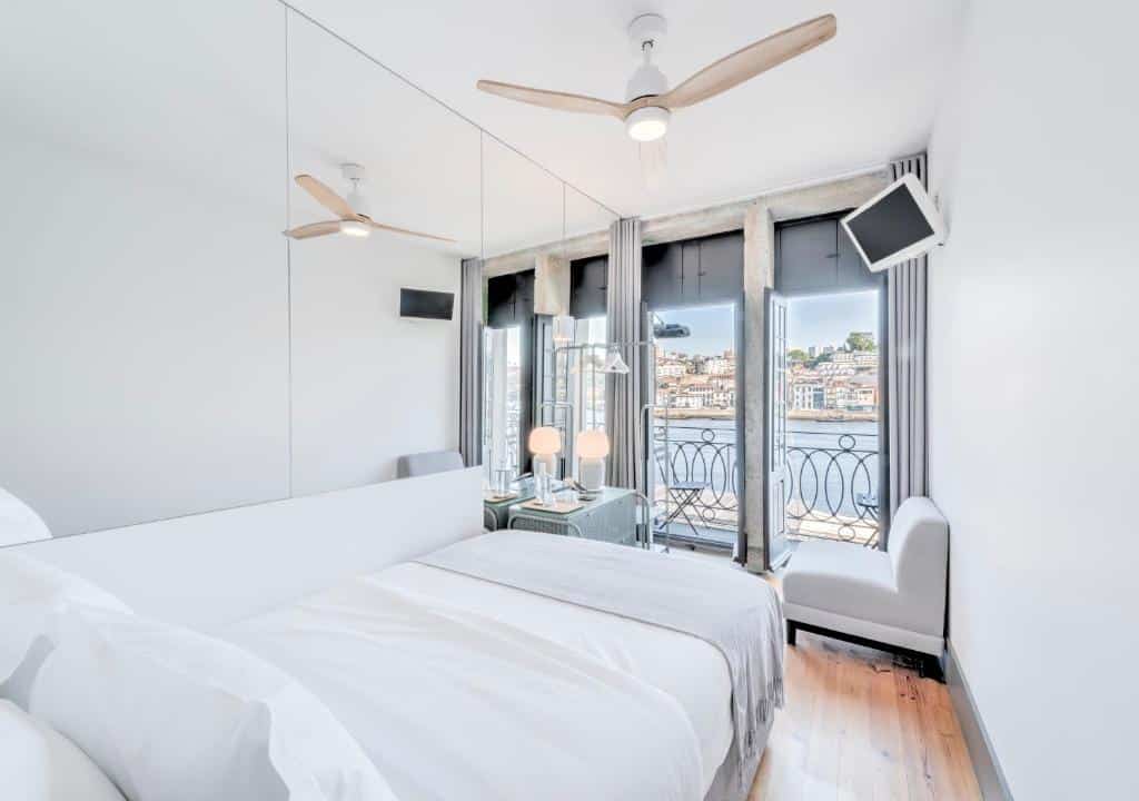 Quarto do Oporto Street Fonte Taurina - Riverfront Suites com cama de solteiro do lado esquerdo da imagem, em frente a cama um poltrona e do lado esquerdo da poltrona portas amplas que dá acesso a varanda. Representa hotéis com vista do Douro.