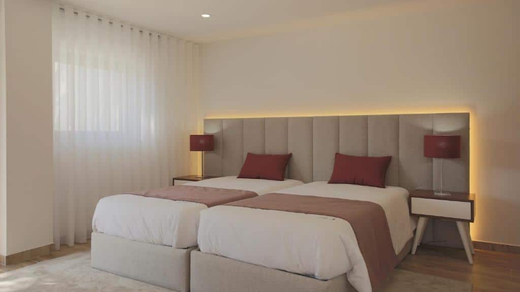 Quarto do Quinta da Portela Douro com duas camas de solteiro juntas do lado no centro da imagem com uma cômoda em cada lado da cama com luminária. Representa hotéis no Vale do Douro.