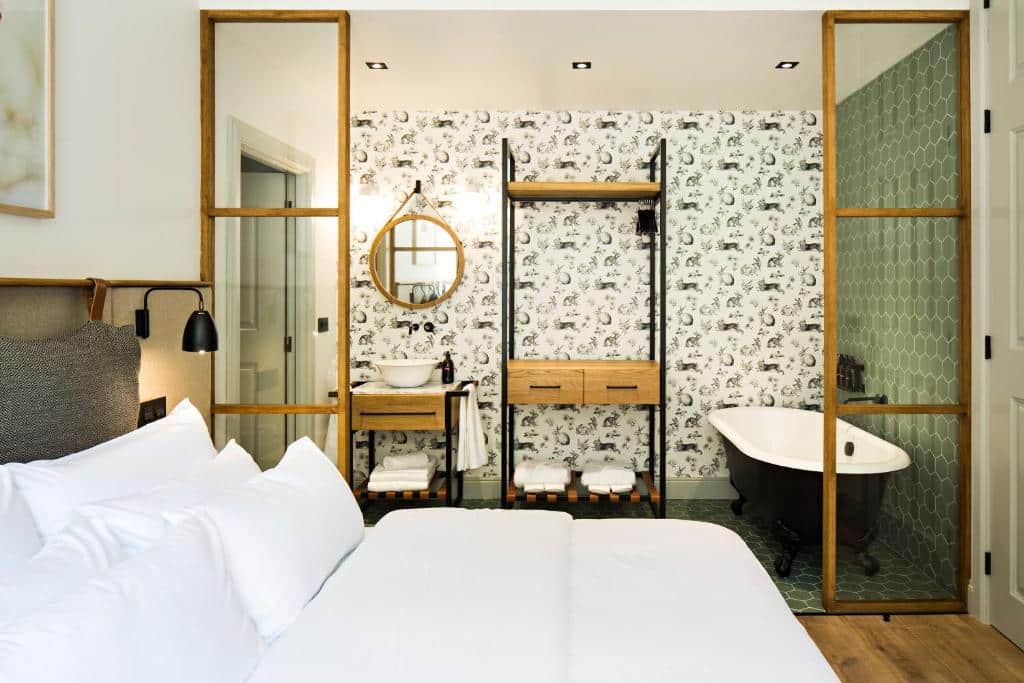 Quarto do Quinta de S.Bernardo – Winery & Farmhouse com cama de casal do lado esquerdo da imagem, do lado esquerdo da cama uma pequena pia e uma banheira de hidromassagem. Representa hotéis no Vale do Douro.