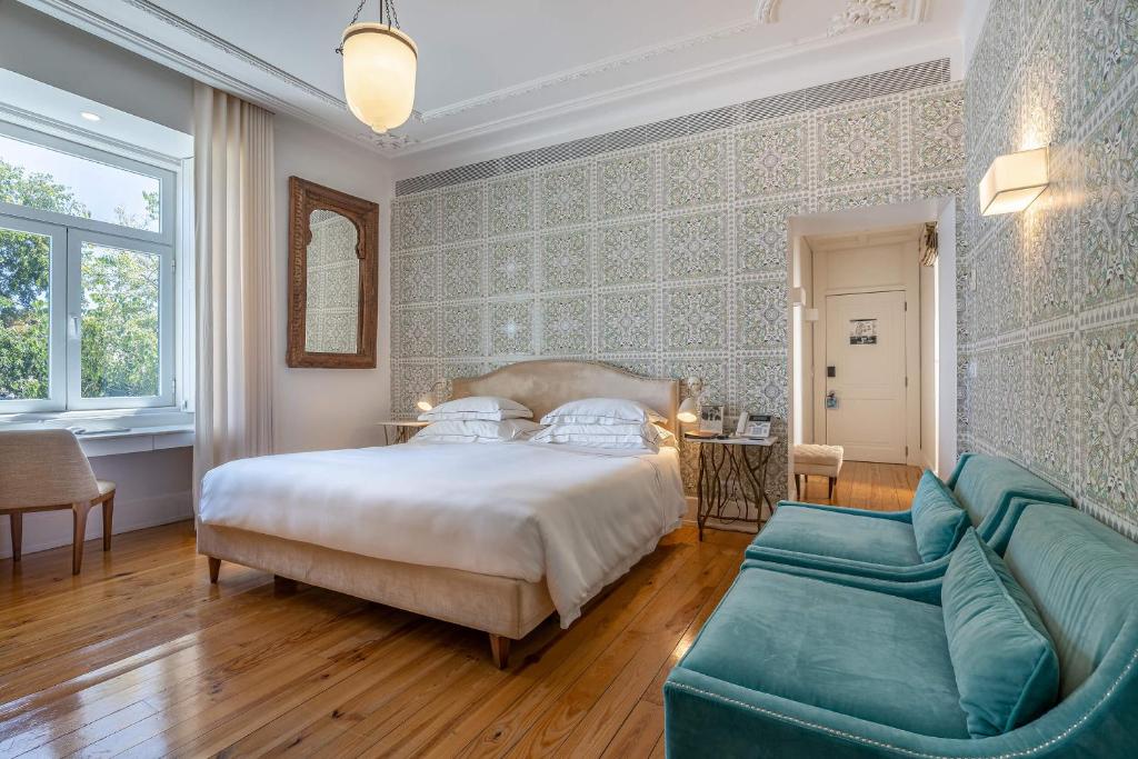 Quarto do Santiago de Alfama - Boutique Hotel com poltronas estofadas do lado direito da imagem, no centro do quarto uma cama de casal com uma cômoda em cada lado com luminária. Representa hotéis para lua de mel em Portugal.