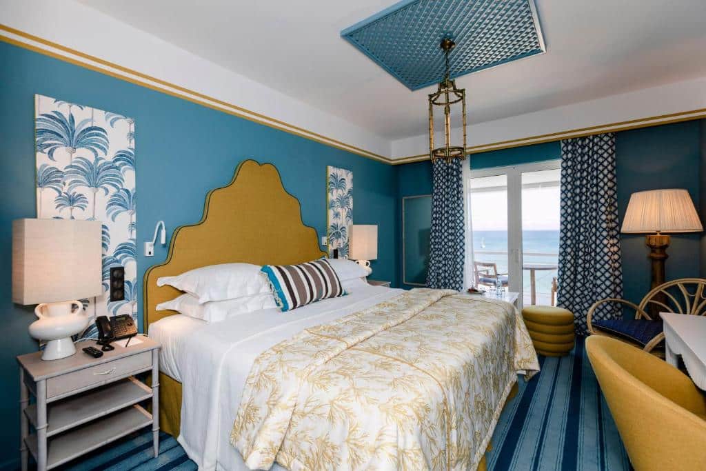Quarto do The Albatroz Hotel com cama de casal do lado esquerdo da imagem, com uma cômoda do lado esquerdo da cama com luminária. Representa hotéis 5 estrelas em Portugal.