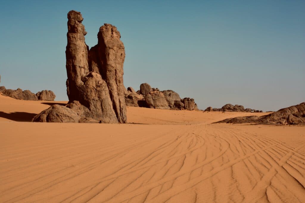 Imagem do planato do Tassili du Hoggar,In Guezzam durante o dia com areia e rochas. Representa seguro viagem Argélia.