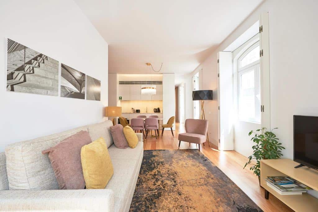 Sala de estar do integrada com uma mini cozinha em um dos apartamentos do Ouro Grand by Level Residences com um sofá com almofadas, um rack com televisão, uma mesa com seis lugares e alguns itens de decoração