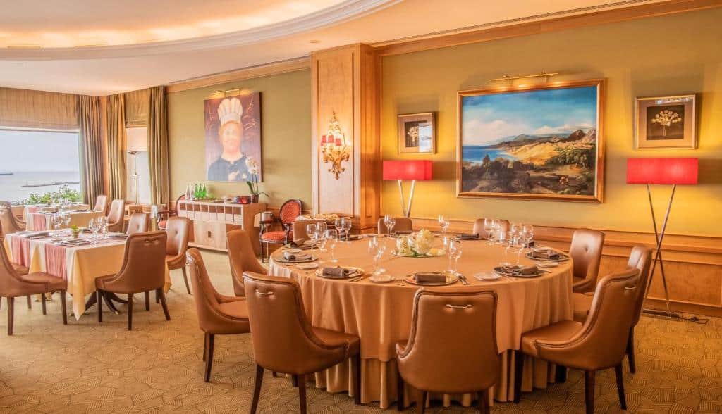 Sala de refeições do Hotel Cascais Miragem Health & Spa com mesas e cadeiras no ambientes e obras de artes na parede.