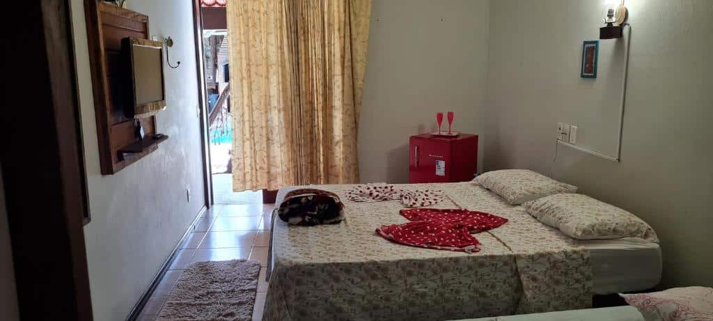 suíte da pousada Gajah em Joinville com uma cama de casal à direita da imagem e uma televisão pendurada na parede, em frente à cama.