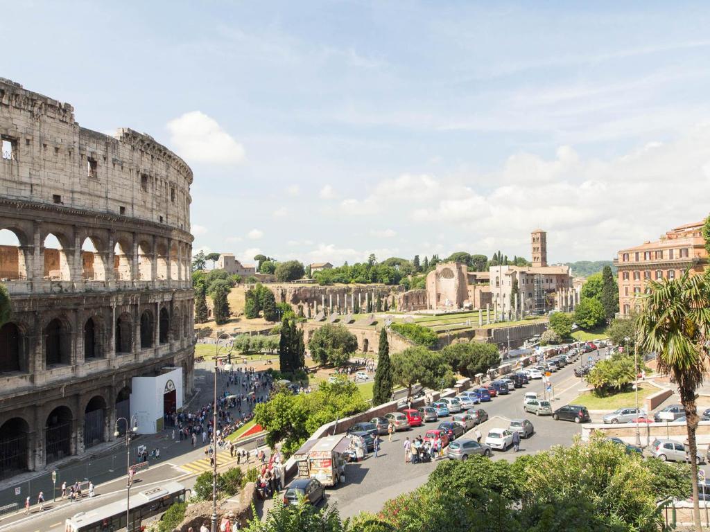 vista do B&B Colosseo Panoramic Rooms, uma das opções de onde ficar em Roma, que dá direto para o Coliseu, há apenas uma rua separando o espaço, e tem vários carros, mais ao longe é possível ver o Fórum Romano