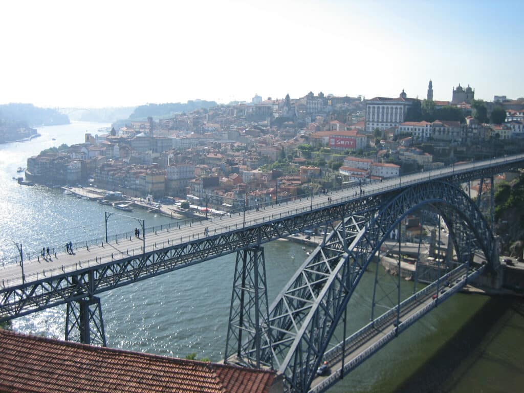 vista da Ponte de Dom Luis I, no Porto, sendo uma ponte muito comprida e alta com boa parte de sua estrutura para baixo, ainda dá pra ver boa parte da cidade, com suas construções e vegetações