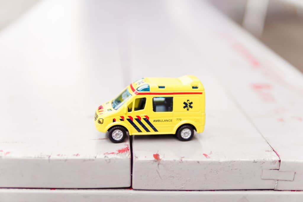 miniatura de uma ambulância amarela em cima de uma mesa de madeira
