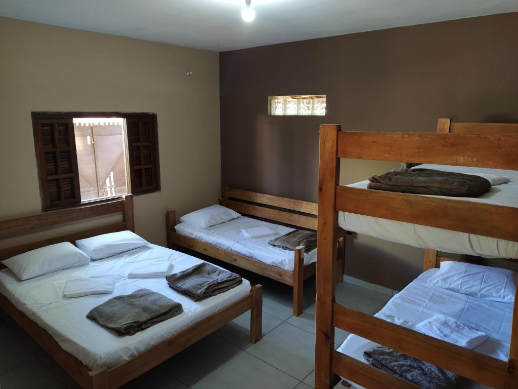Quarto do Apartamentos Chapéu de Sol. Uma cama de beliche do lado direito, no lado esquerdo uma cama de casal, uma cama de solteiro e a janela do quarto.