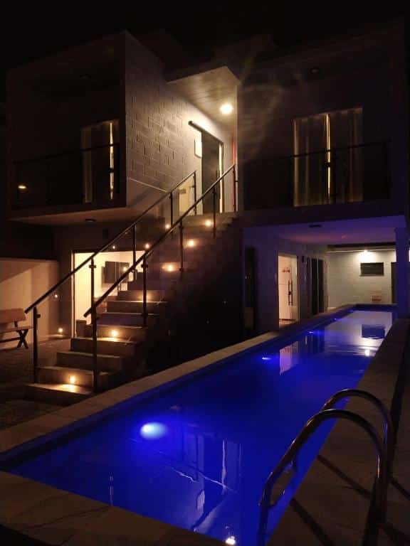 Área externa do Balli Suítes. Uma piscina no lado direito, no lado esquerdo a escada com os quartos e sacadas em cima.