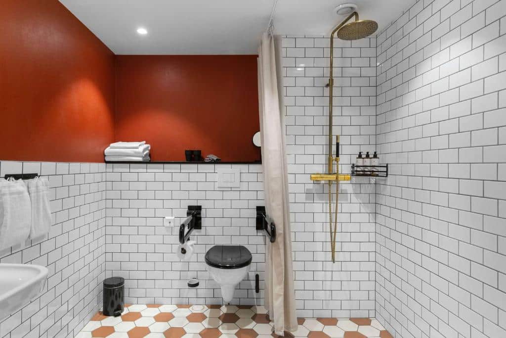 Banheiro com acessibilidade do The Winery Hotel, WorldHotels Crafted com pia do lado esquerdo a frente, já ao fundo vaso sanitário com barras de apoio e do lado direito o chuveiro.