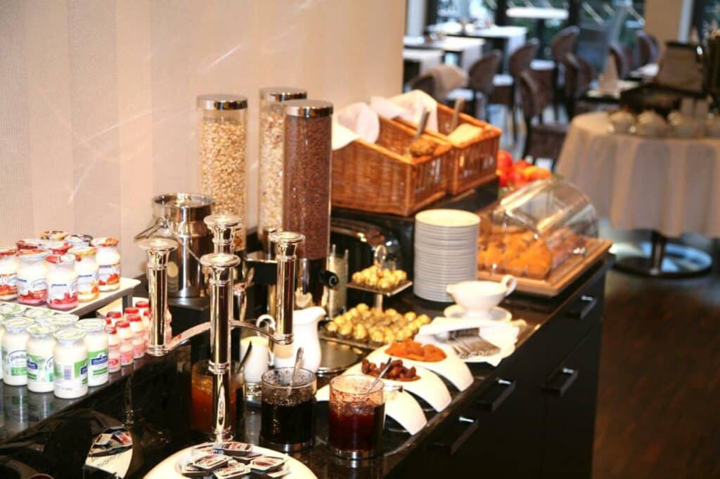 Mesa de café da manhã do Hotel Favor com geleias, grão e pães em cima da mesa.
