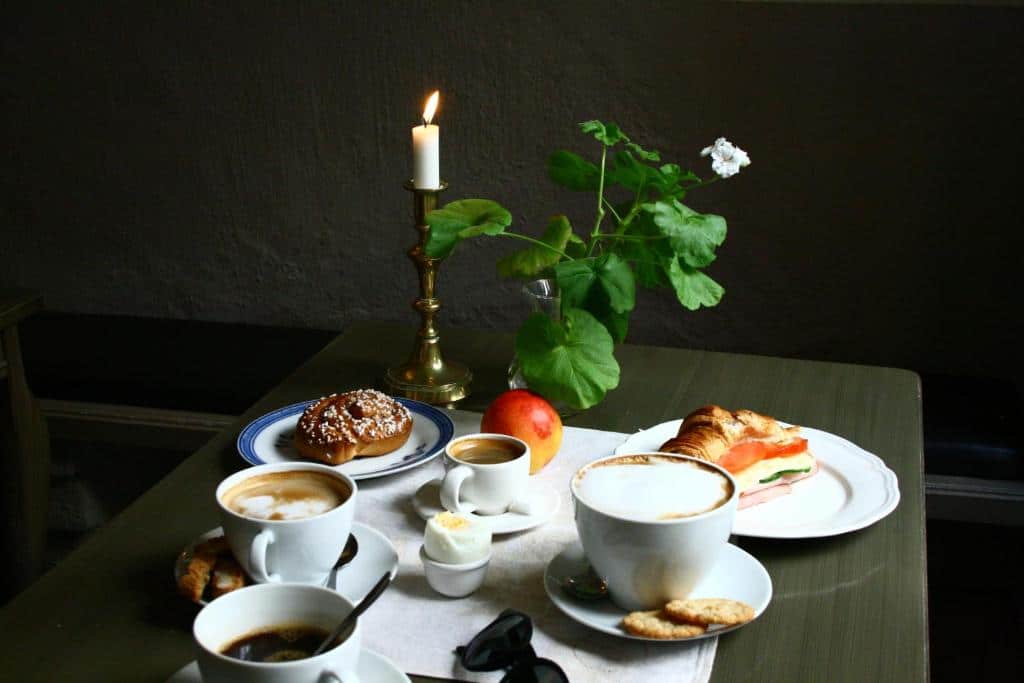 Mesa de café da manhã do Hotel Sven Vintappare com cafés e pães em cima da mesa.