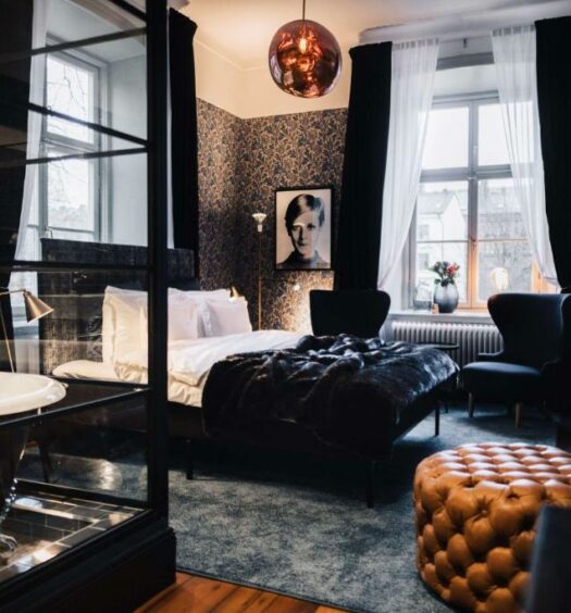 Quarto do NOFO Hotel, WorldHotels Crafted com banheira de hidromassagem do lado esquerdo da imagem a frente, já ao fundo cama de casal e do lado esquerdo da cama a frente uma poltrona. Representa hotéis em Estocolmo.