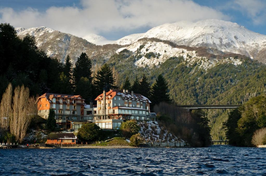 O prédio do hotel Correntoso Lake & River Hotel no canto esquerdo. Atrás as montanhas, e na frente e ao redor o lago. Foto para ilustrar post sobre hotéis em Villa La Angostura.