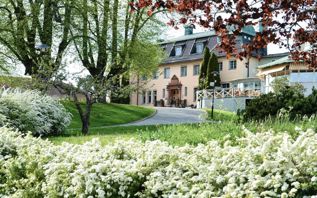 Frente do Såstaholm Hotell & Konferens durante o dia com jardim florido a frente com árvores e ao fundo a hospedagem.