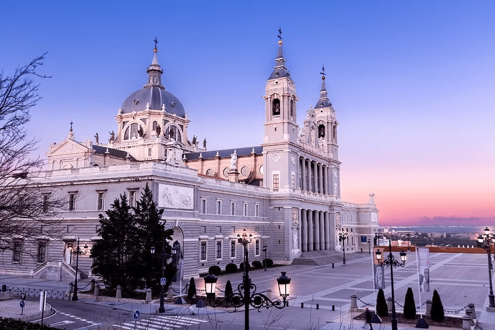 Vista da Catedral de Almudena, uma estrutura imponente em tons claros e bastante trabalhada com uma praça à frente