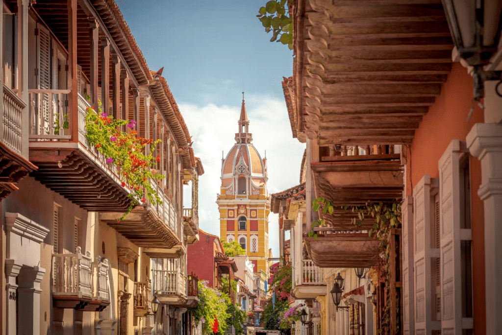 Ruas com arquitetura charmosa e florzinhas nas janelas coloridas, bem como uma igreja ao fundo em tons de amarelo e vermelho em Cartagena, na Colômbia