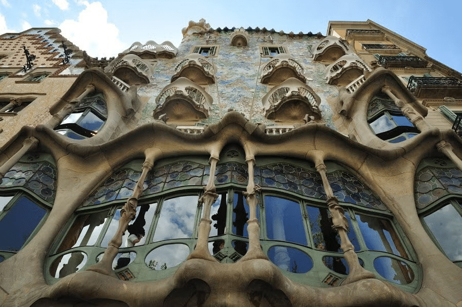 Vista de baixo para cima da Casa Batlló, em Barcelona, com janelas e sacadas sinuosas, além de vidros que acompanham o desenho da fachada, que é estilizada com cores suaves e texturizada