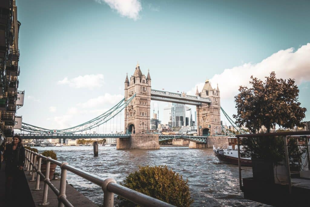 Torre de Londres vista de uma das margens do Rio Tâmisa, em um dia de céu claro com poucas nuvens