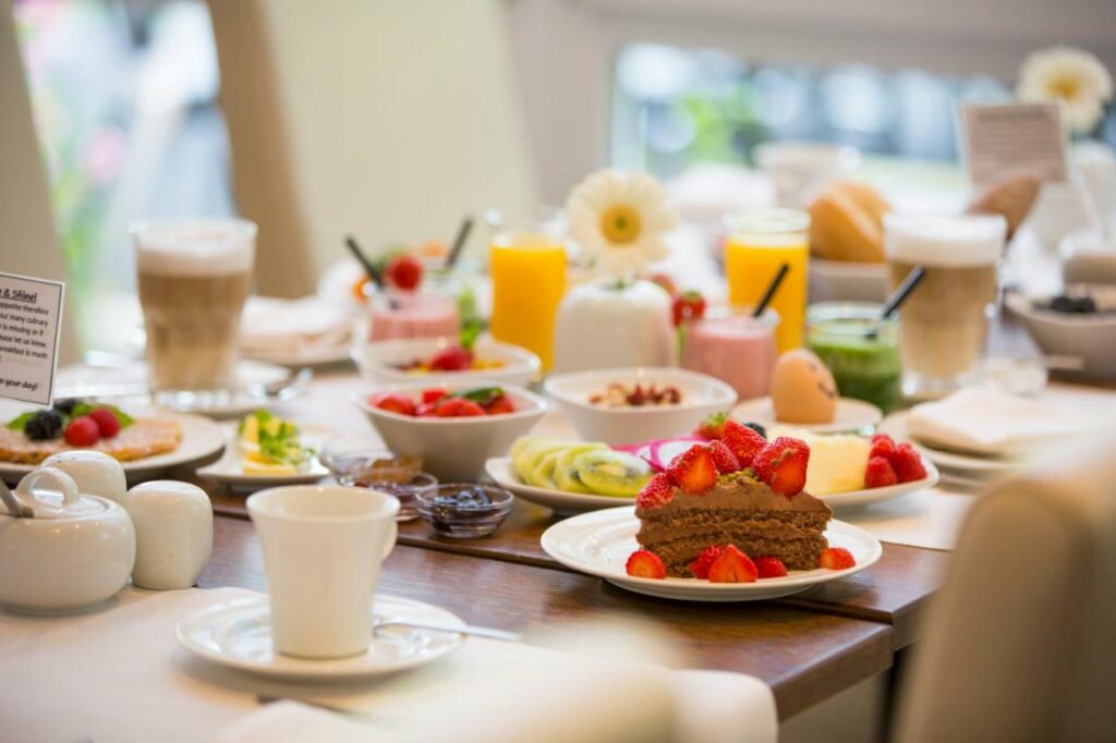 Mesa de café da manhã do Auszeit Hotel Düsseldorf – das Frühstückshotel – Partner of SORAT Hotels  com pães, frutas e café na mesa.
