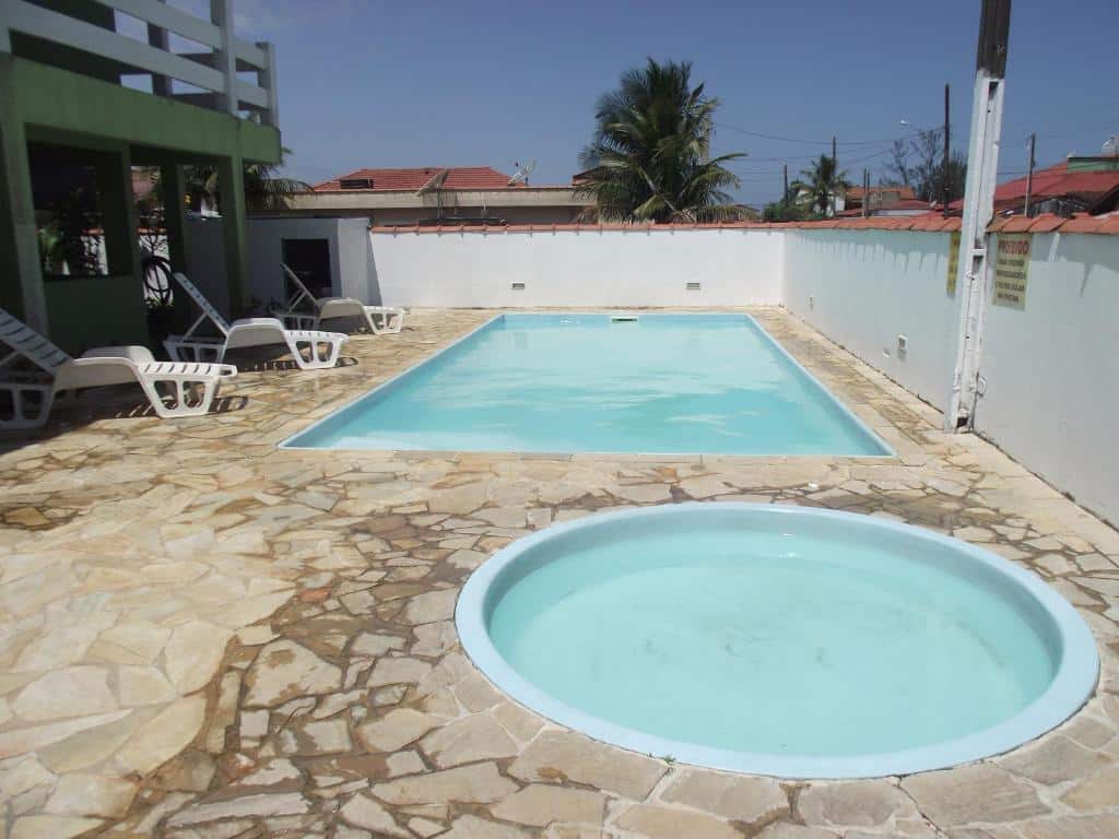 Piscina ao ar livre da Pousada Canto da Ilha. Uma piscina infantil redonda na frente e outra piscina grande atrás. Do lado esquerdo cadeiras de tomar sol. Ao redor o muro da pousada.