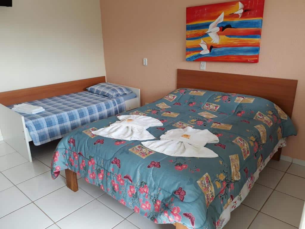 Quarto da Pousada Canto da Ilha. Uma cama de casal do lado direito e uma cama de solteiro do lado esquerdo. Foto para ilustrar post sobre pousadas em Ilha Comprida.