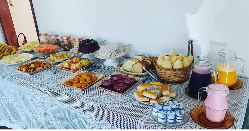 Mesa do café da manhã da Pousada da Jaqueira - EPP com algumas opções de pães, sucos, doces e frutas, ilustrando post Pousadas em Rio das Ostras.