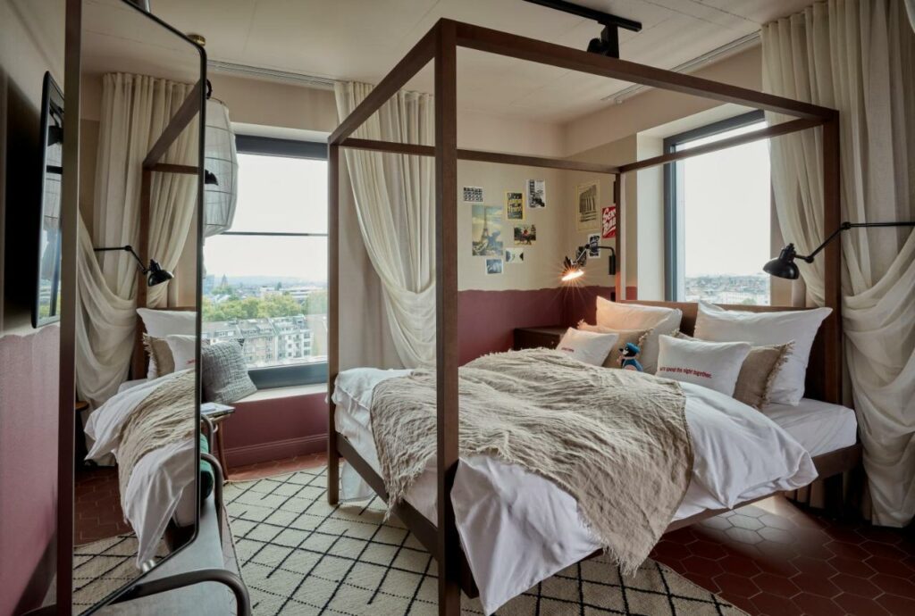Quarto do 25hours Hotel Das Tour com cama de casal do lado direito da imagem. Representa hotéis em Dusseldorf.