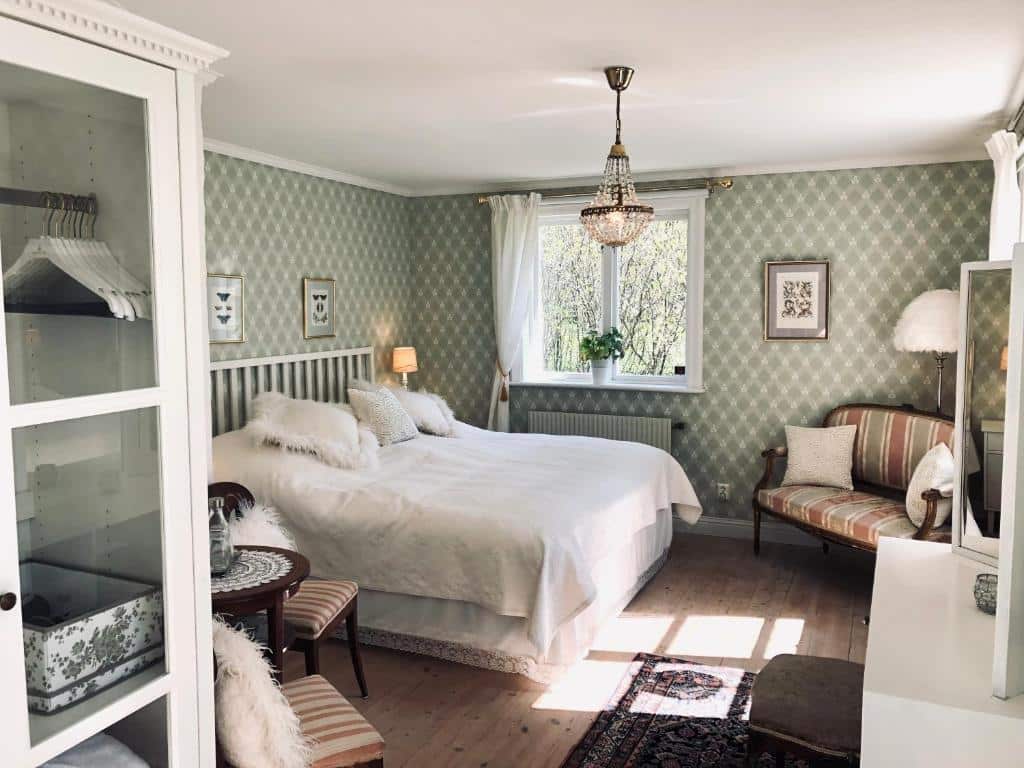 Quarto do Engsholms Slott – Adults Only com cama de casal do lado esquerdo da imagem, do lado esquerdo da cama a frente um sofá. Representa hotéis em Estocolmo.