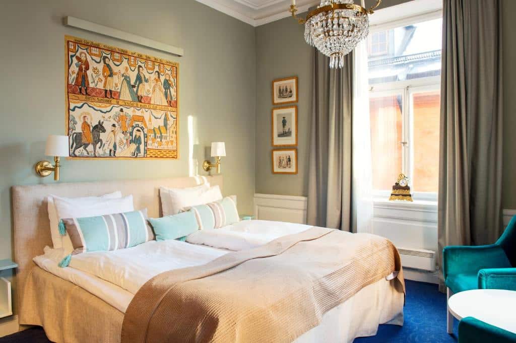 Quarto do Lady Hamilton Hotel com cama de casal do lado esquerdo da imagem a frente a cama do lado esquerdo da cama uma poltrona. Representa hotéis em Estocolmo.