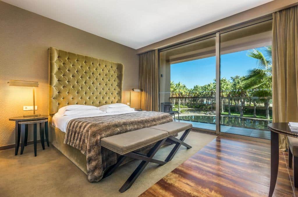 Quarto do Lago Montargil & Villas com cama de casal do lado esquerdo da imagem com duas cômodas em cada lado da cama e um banco no pé da cama. Representa hotéis para lua de mel em Portugal.