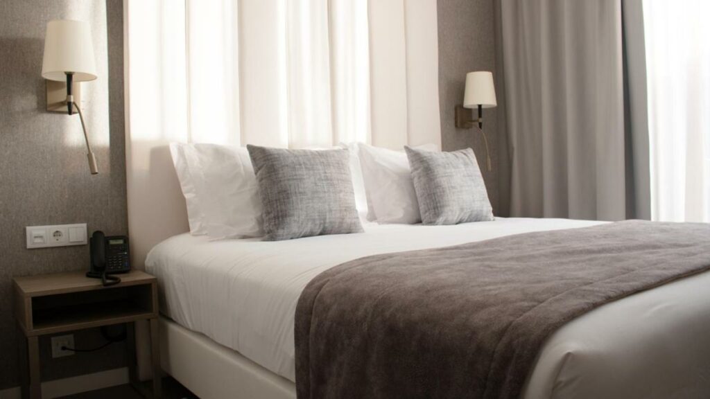Quarto do MASA Hotel & Spa Campo Grande Collection com cama de casal do lado esquerdo da imagem com uma cômoda do lado direito da cama. Representa hotéis all inclusive em Portugal.