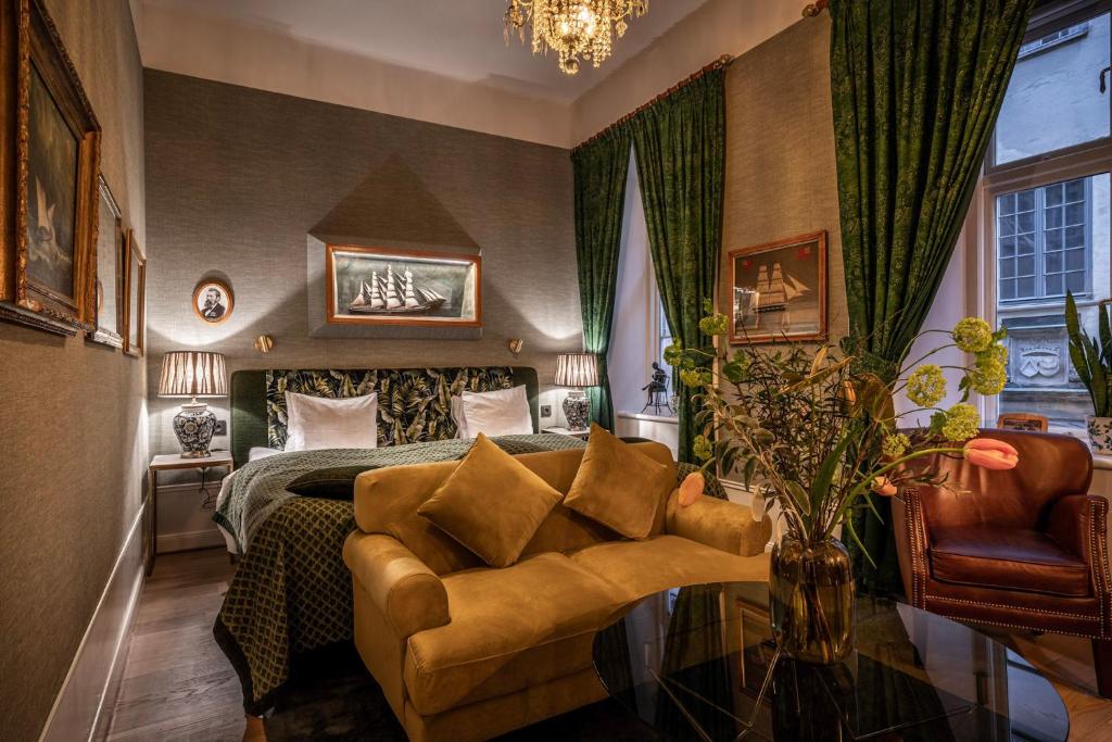Quarto do Victory Hotel com sala de estar a frente com mesa redonda e sofás, já ao fundo cama de casal com uma cômoda em cada lado da cama com luminária. Representa hotéis em Estocolmo.