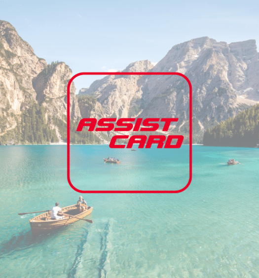Um lago em verde claro com alguns barcos passando, ao fundo há diversas montanhas, para representar a seguradora Assist Card
