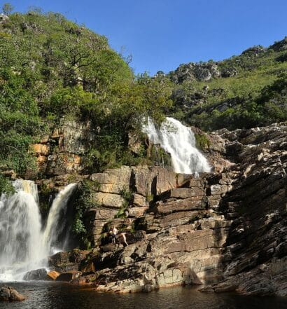 Cachoeira das Andorinhas, um local com duas quedas d'água com diversas rochas e vegetação ao redor, para representar a Serra do Cipó em Minas Gerais