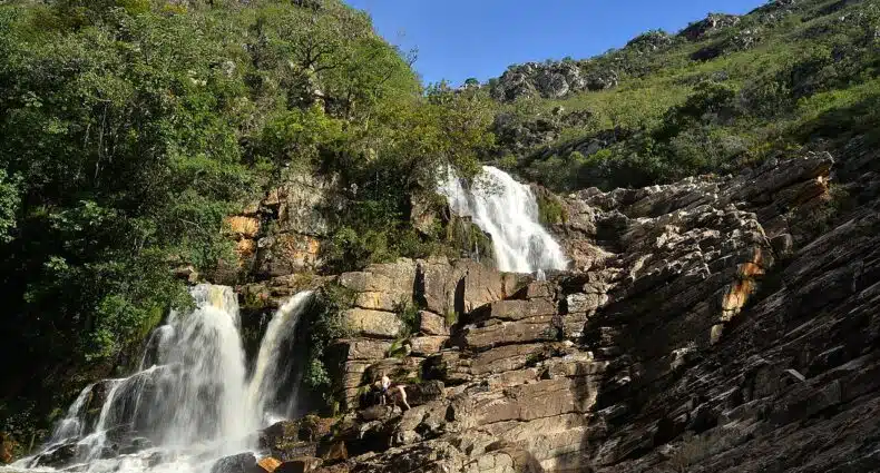 Cachoeira das Andorinhas, um local com duas quedas d'água com diversas rochas e vegetação ao redor, para representar a Serra do Cipó em Minas Gerais