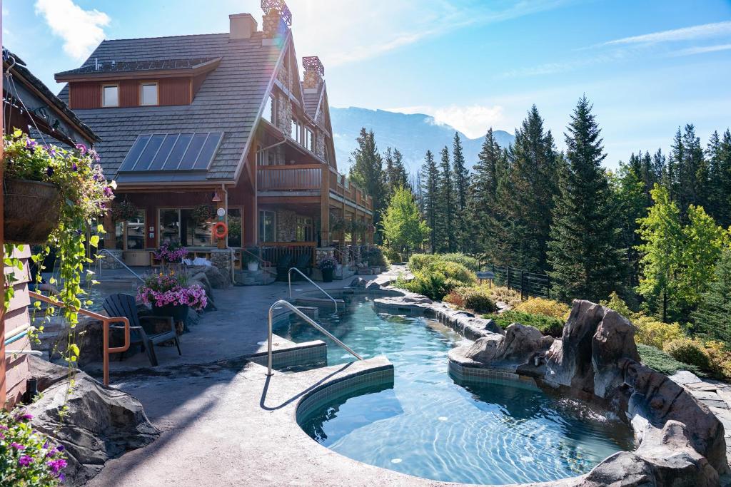 Parte do The Hidden Ridge Resort que mostra parte da construção do hotel com três andares e telhados pontudos e ao lado uma piscina ao ar livre com vista para as árvores verdes durante o dia, ilustrando post Hotéis em Banff.