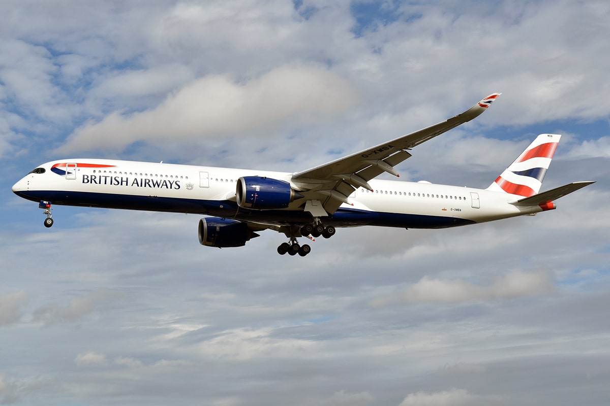 Um avião da British Airways no ar, ele é branco com detalhes em vermelho e azul, para representar British Airways