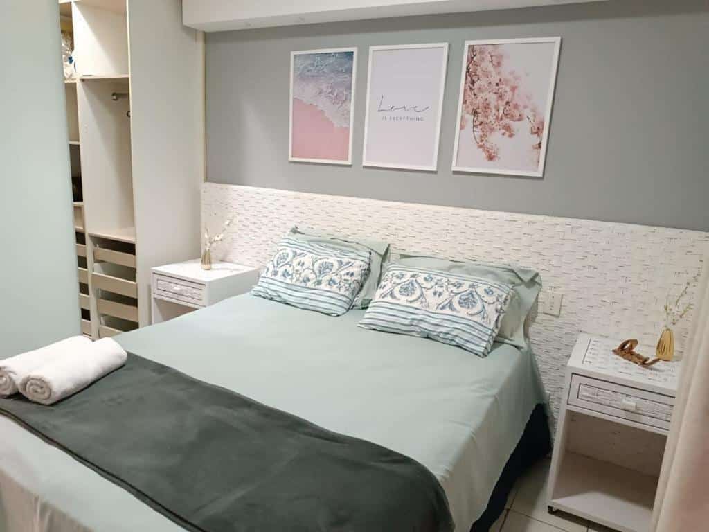 A cama está encostada na parede do lado direito, há uma pequena cômoda em cada lado da cama e no lado esquerdo há um armário com prateleiras e gavetas sem porta. Imagem para ilustrar o post airbnb em Angra dos Reis.