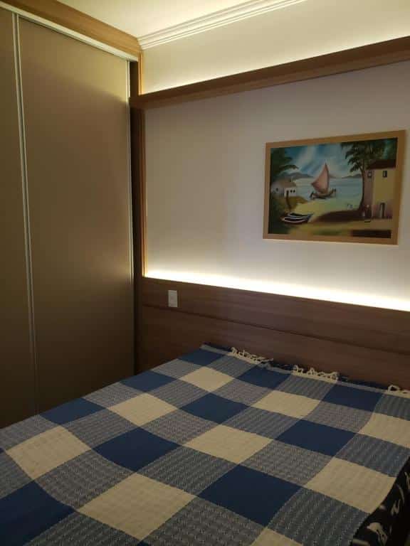 Quarto do Apartamento agradável em Ubatuba . Uma cama de casal na frente, no lado esquerdo o armário, no fundo uma luz ambiente.