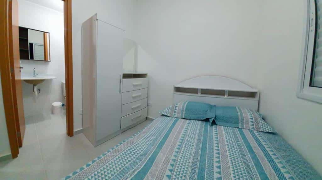 Quarto do Apartamento novo. Uma cama de casal do lado direito, do lado esquerdo uma cômoda e a porta do banheiro aberta. Foto para ilustrar post sobre airbnb em Perequê Mirim.